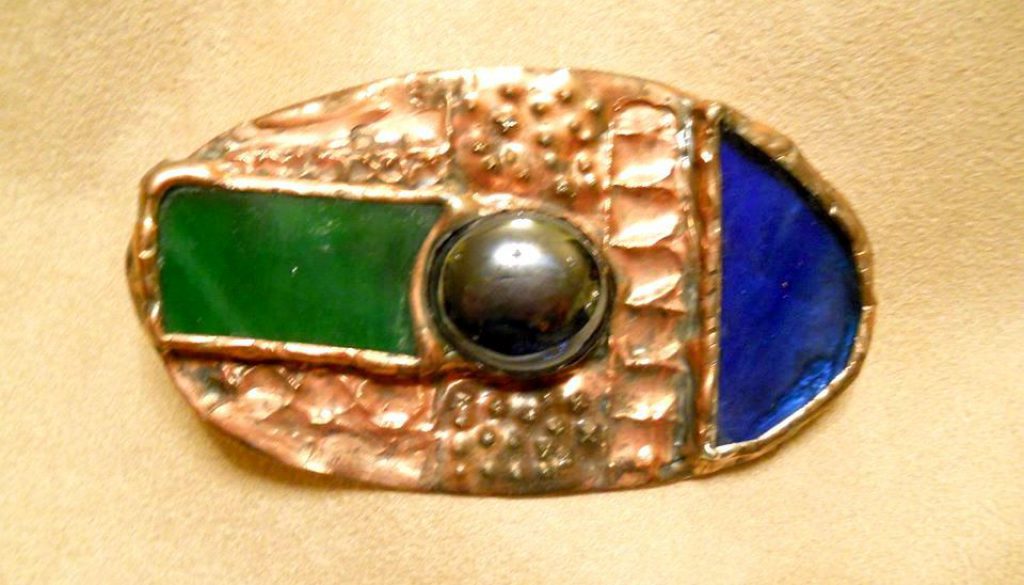spilla in lamina di rame sbalzato e inciso a mano con vetri opalescenti e gemma di vetro in lega argento patinata con tecnica Tiffany