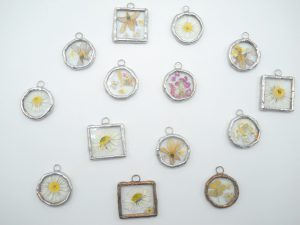 ciondoli composti da fiorellini di campo veri, incastonati tra vetri trasparenti in lega argento con tecnica Tiffany