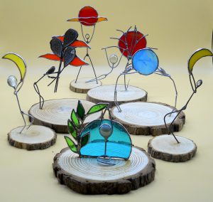 figurine stilizzate in filo di ferro, vetri artistici, specchi e legno
